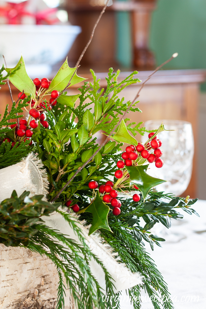 Side view of a Christmas centerpiece in a Birch bark box with greenery, Holly, twigs, and white bows